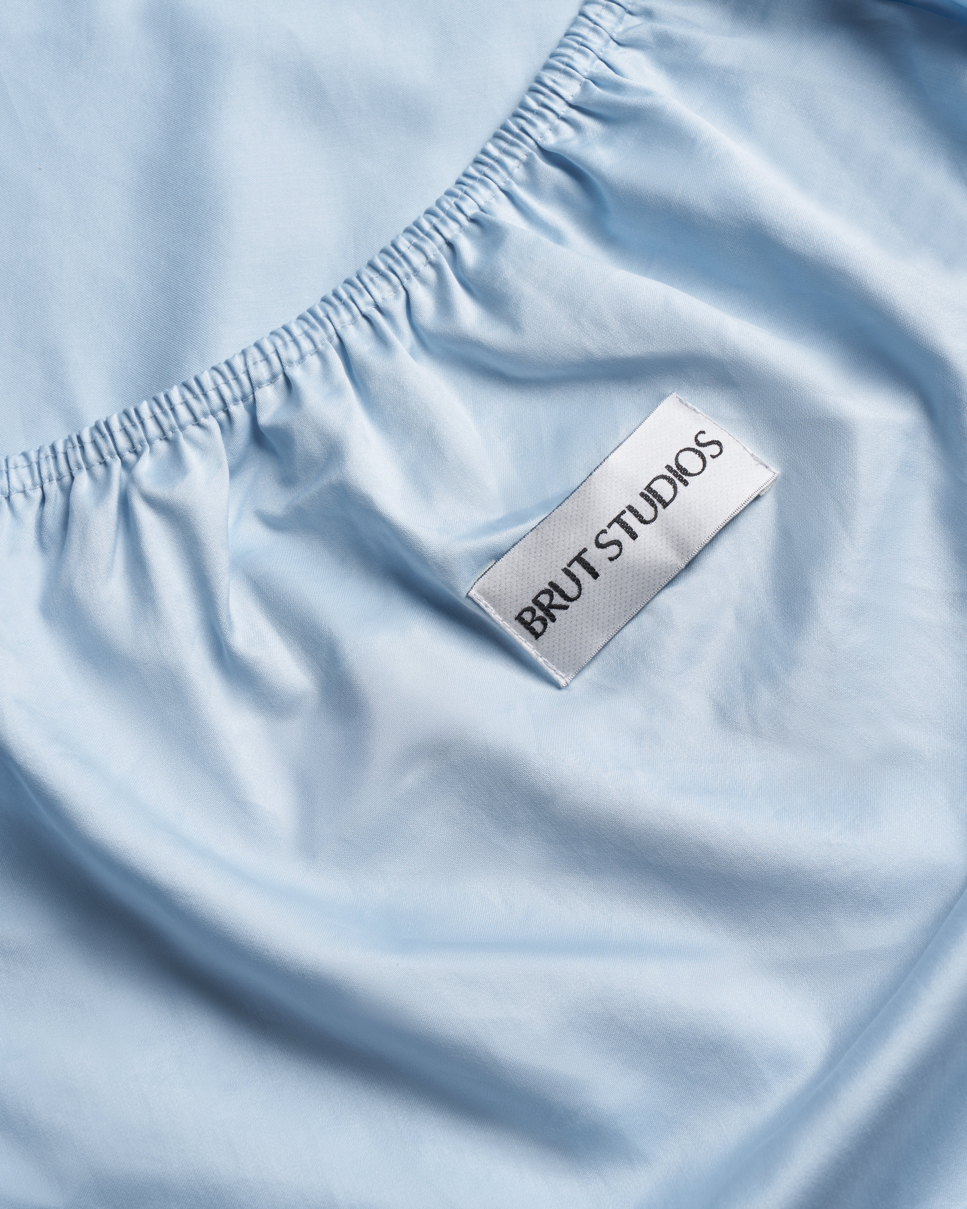 Concrete Blue sateen fitted sheet, styled on bed